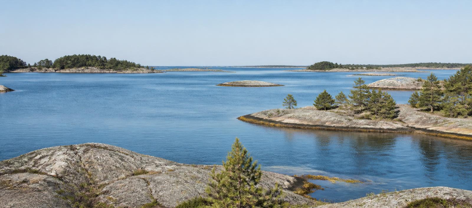 Granite skerries and pine islands along a calm Baltic coastline in clear summer light