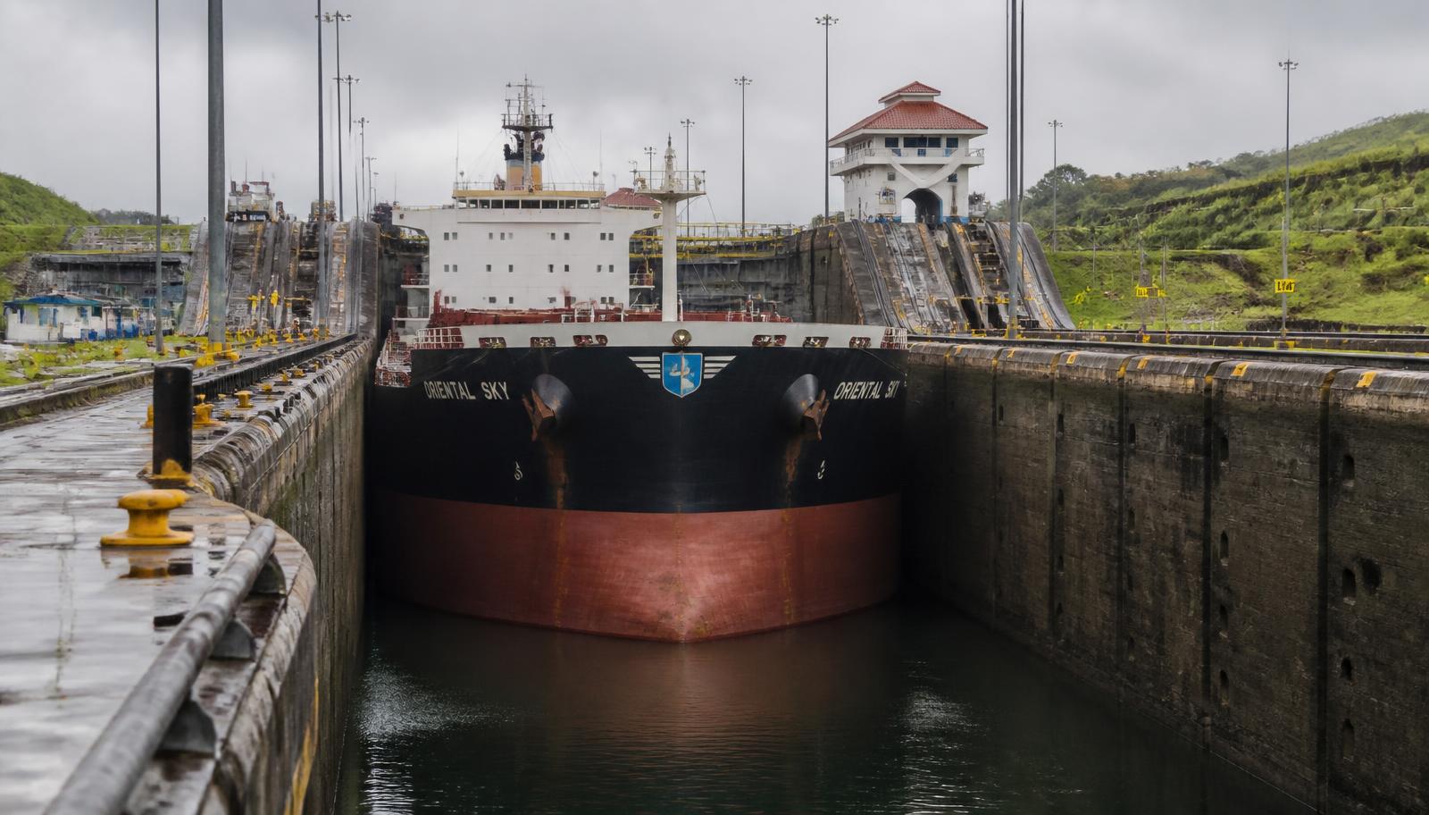 A ship inside a canal lock chamber whose walls sit close to both sides of the hull