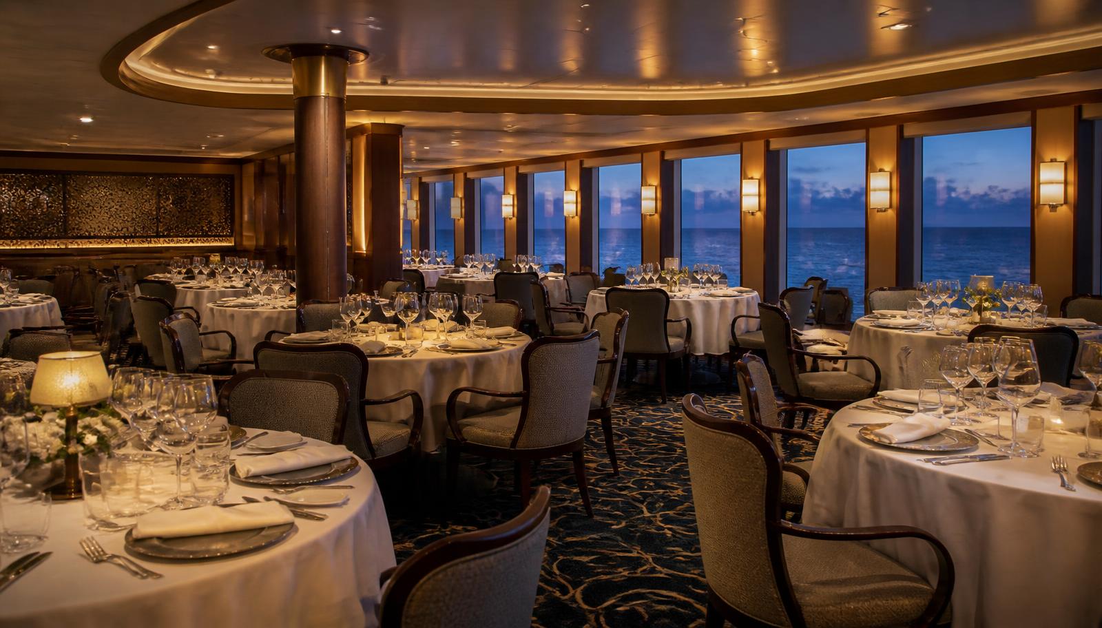 An ocean ship's main dining room laid for service, one of the areas where what a fare includes and what it does not is decided.